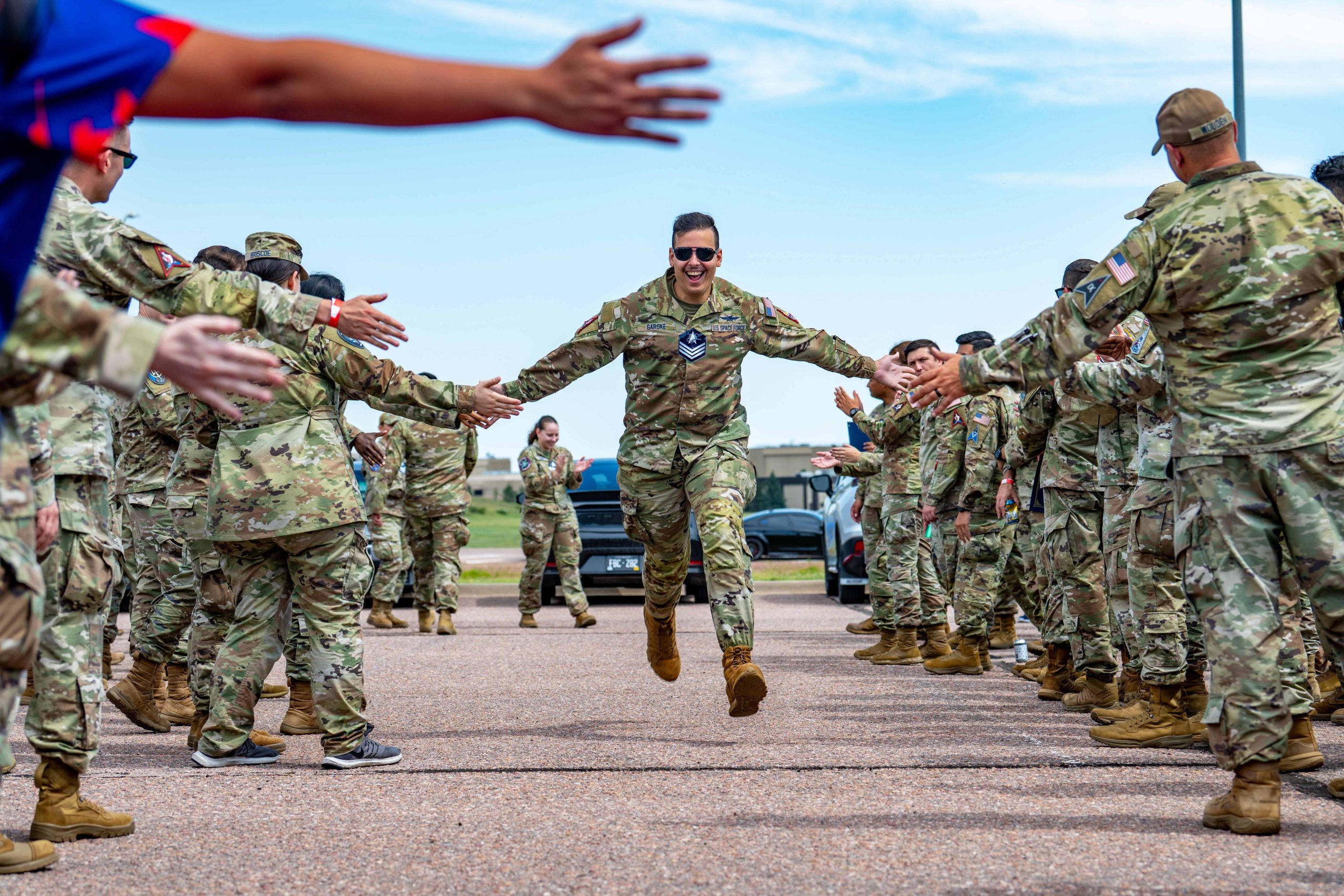 SCHRIEVER SPACE FORCE BASE, Colo--U.S. Space Force Spc. 4 Nikolaos Garske, 15th Cyber Squadron cyber host analyst, receives congratulations while running through a ceremonial gauntlet after being selected for promotion to Sergeant during a Guardian promotion release ceremony at Schriever Space Force Base, Colorado, July 25, 2025. The ceremony celebrated the dedication, leadership, and hard work of Guardians selected for promotion to Sergeant, Technical Sgt. and Master Sgt., marking a proud milestone in their careers and service to the mission. (U.S. Space Force photo by Tiana Williams)