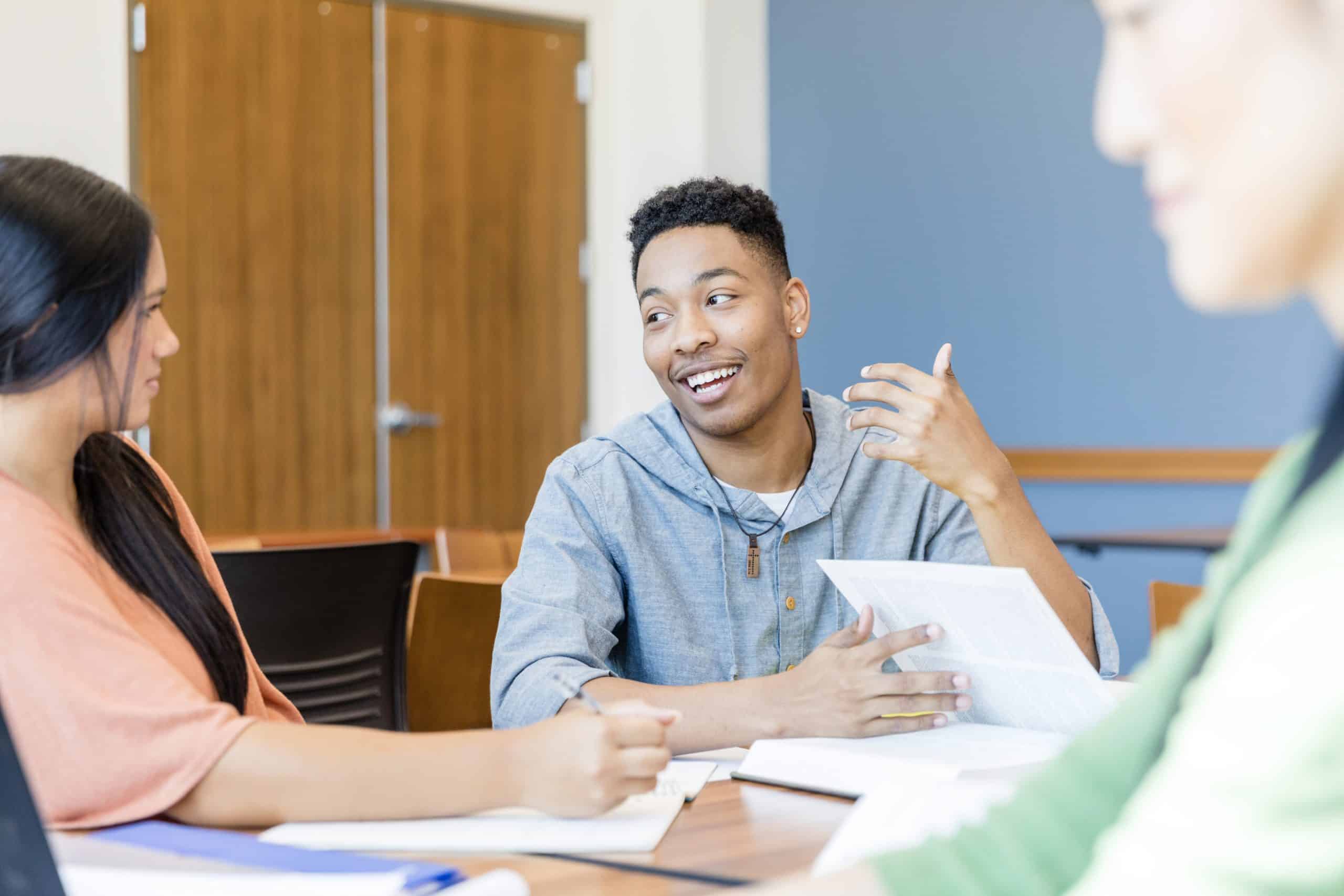 Two young adults study together; a man and woman engage in lively discussion.